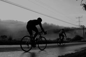 Ciclistas de ruta en la calle con fondo bosque en blanco y negro, Haute Route México con Altius Events